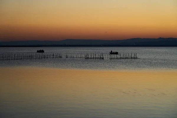 落日落在湖上 小船上 船上有许多人 — 图库照片