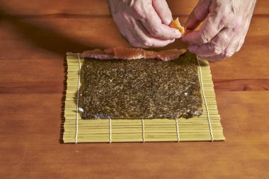 Aşçı pilavı yosun örtüsüne serer ve balığı bir ucuna koyar.