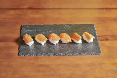 Bambu masasında çeşitli balık ve pirinç suşilerinin sunumu