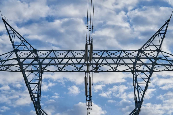 high voltage electricity tower in a rural area with a nice blue sky with some flashy clouds