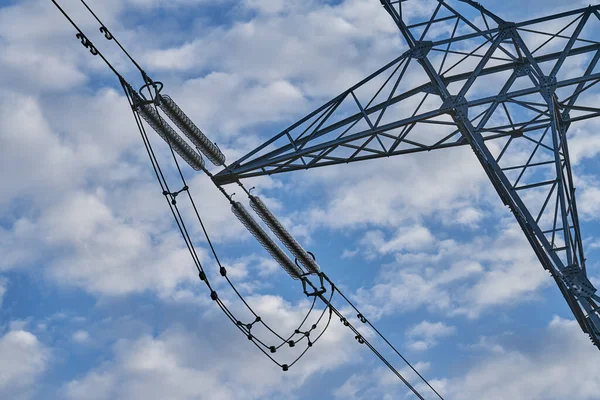 high voltage electricity tower in a rural area with a nice blue sky with some flashy clouds