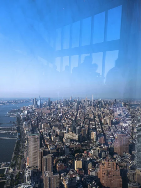 Manhattan 'ın panoramik manzarası, Dünya Ticaret Merkezi binasının üst katlarındaki cam pencerelerden çekilen görüntüler, içerideki bazı insanların yansımalarını görebilirsiniz.