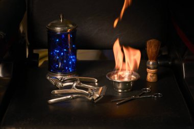 Eski berber aletleri, ustura, kase ve bileme aleti, ve mavi kap, deri malzemelerinin koyu arkaplanda dezenfekte araçları,