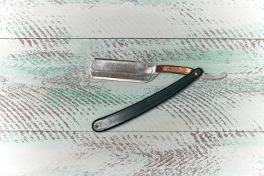 Eski berber aletlerinin sunumu bir ustura, beyaz boyalı ahşap bir arka plan üzerinde