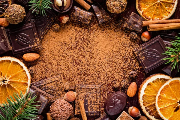 Chocolate, chocolate bars, candies, spices, fir tree, dried orange rings and cocoa powder - frame with copy space. — Stock Photo, Image