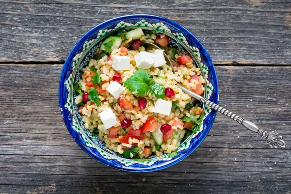Tabbouleh salad with bulgur, pomegranate seeds and fresh white cheese — Stock Photo, Image