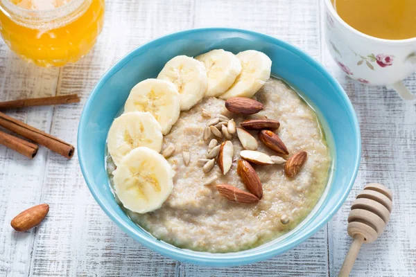Oatmeal porridge with bananas, honey, nuts and seeds — Stock Photo, Image
