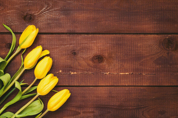 Yellow tulips on rustic wooden background