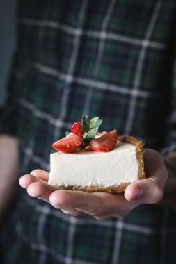 Parçası cheesecake el üstünde tutan