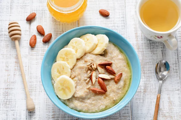 Porridge di farina d'avena con banane e mandorle e tazza di tè verde per una colazione sana — Foto Stock