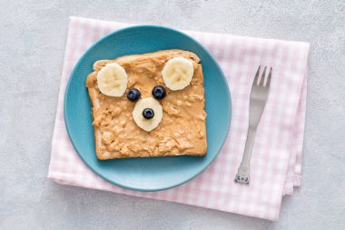 Oyuncak ayı fıstık ezmeli tost mavi tabakta. Çocuklar için gıda