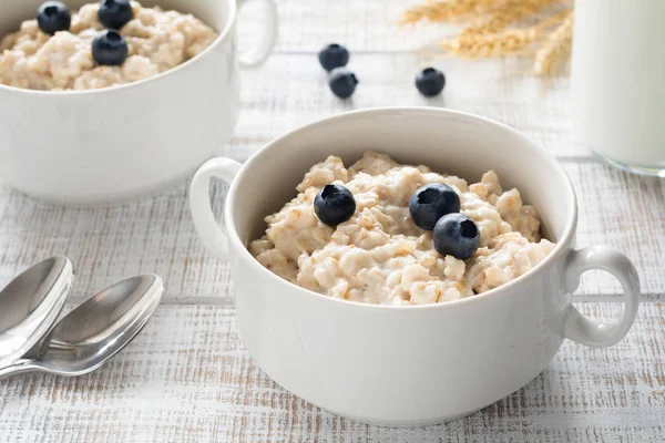 Oatmeal porridge in bowl with fresh blueberries — Stock Photo, Image