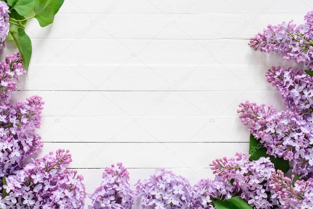 Lilacs on white wooden background. Floral frame