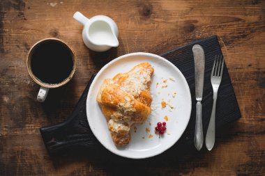 Kruvasan, kahve ve krem koyu kesme tahtası üzerinde