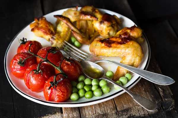 Alitas de pollo picantes, tomates cherry asados y guisantes verdes. Comida baslanced —  Fotos de Stock