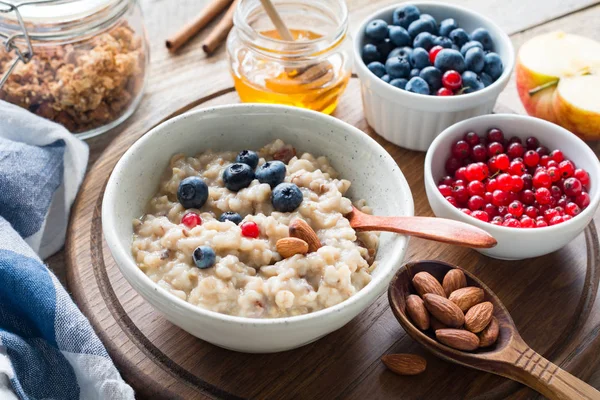 Oatmeal porridge with berries, honey and nuts — Stock Photo, Image