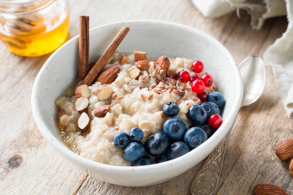 Porridge di farina d'avena con miele, bacche e semi in ciotola — Foto Stock