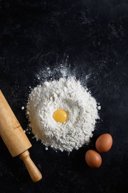 Un, yumurta ve oklava koyu arka plan üzerinde