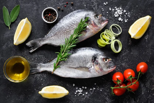 Pescado dorado o besugo fresco sin cocer con rodajas de limón, especias, hierbas y verduras. Comida mediterránea. Vista superior —  Fotos de Stock