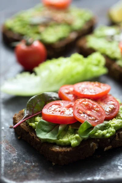 Vegan toast with avocado, spinach and tomato. Closeup view