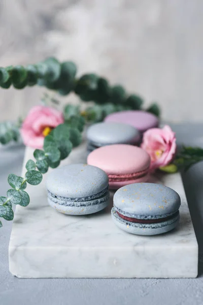 Pastel macaroons or macarons and flowers on marble — Stock Photo, Image
