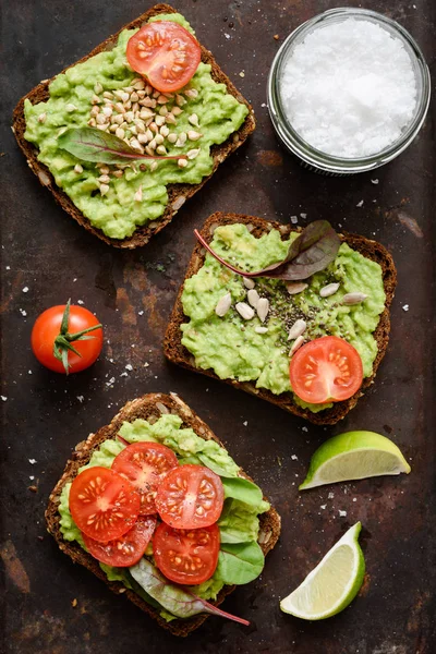 Nuttige avocado toast met spruiten, tomaat, zaden en zee zout vlokken — Stockfoto