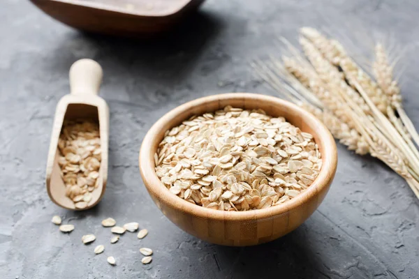 Copos de avena en cuenco de madera y espigas de trigo dorado —  Fotos de Stock