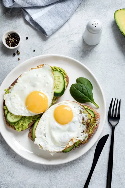 Fried egg, avocado and cucumber on whole grain toasted bread