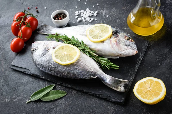 Pescado blanco sin cocer, aceite de oliva, limón y especias sobre pizarra —  Fotos de Stock