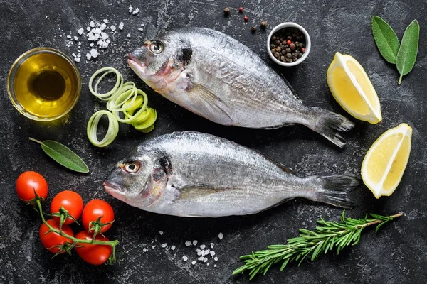 Pescado de mar fresco Dorado o Sea Bream con hierbas y especias sobre fondo de pizarra listo para cocinar —  Fotos de Stock