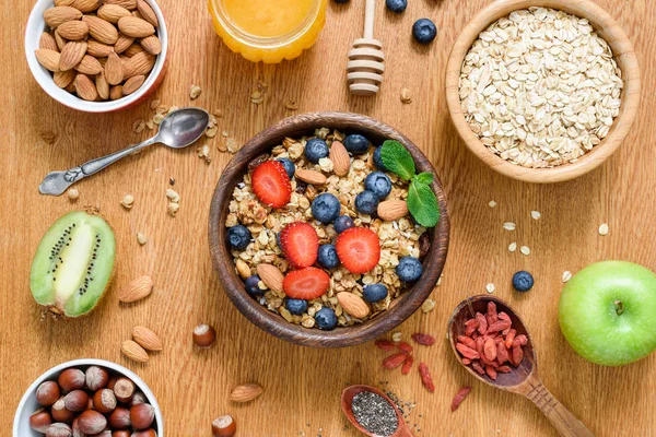 Gesundes Frühstücksbuffet auf Holztisch. Müsli, Hafer, Nüsse, Honig und frisches Obst — Stockfoto