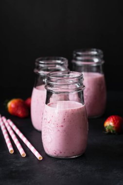 Çilek güler yüzlü veya koyu arka plan üzerinde kavanoza milkshake