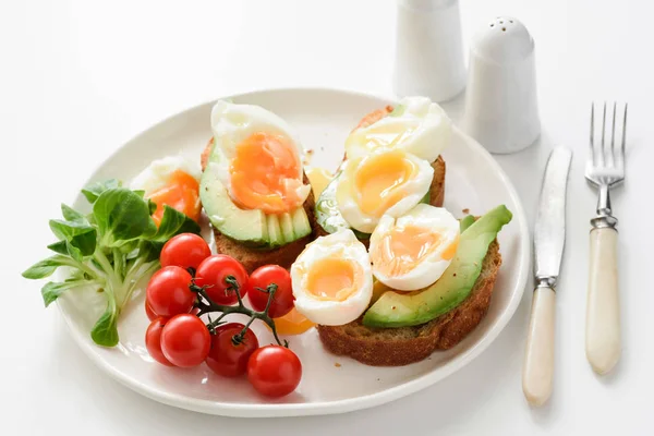Яйцо и тосты с авокадо на белой тарелке, вид крупным планом — стоковое фото