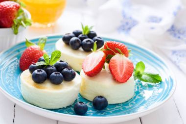Mavi plaka üzerinde taze çilek ile Mini cheesecakes ya da syrniki ya süzme peynirli gözleme