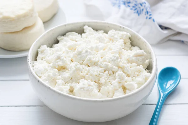 Tvorog, Bauernkäse, Quark oder Quark in weißer Schüssel auf weißem Holztisch — Stockfoto