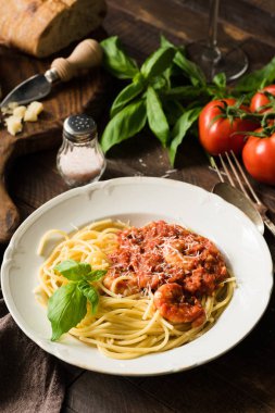 Spagetti domates sosu, rendelenmiş parmesan peyniri ve karides rustik ahşap masa üzerinde