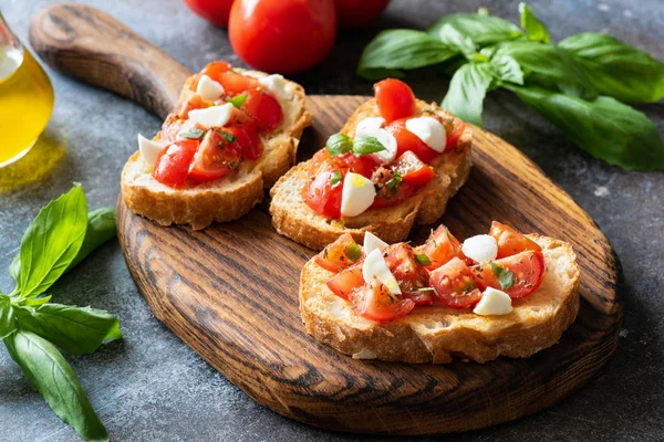 Bruschetta kiraz domates ve mozzarella peyniri ahşap kesme tahtası üzerinde