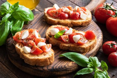 Bruschetta ahşap tahta üzerinde domates, fesleğen ve mozzarella peyniri ile
