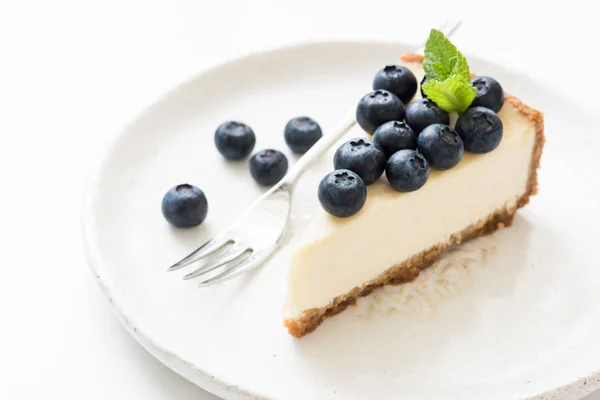 Scheibe Käsekuchen mit Blaubeeren und Minzblättern auf weiß — Stockfoto