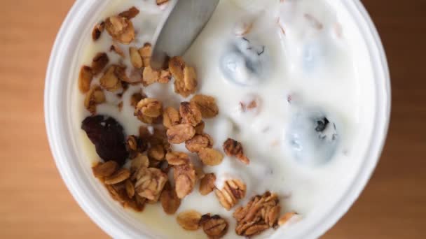 酸奶加麦片和蓝莓在塑料瓶里 把一汤匙的酸奶和麦片放在一起吃 健康早餐或零食 清洁饮食概念 — 图库视频影像