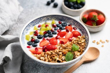 Yoğurt, granola, böğürtlen ve meyveli kahvaltı kasesi.