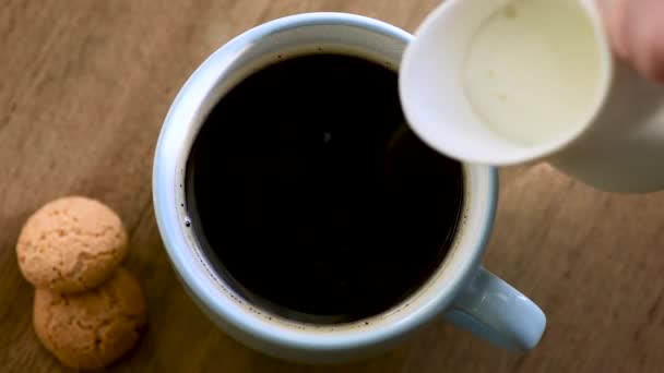 黒コーヒーのカップにクリームを入れて コーヒーとクリームを混ぜる クローズアップビュー — ストック動画