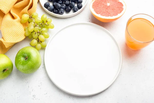 Fresh organic fruits, fruit juice and empty white plate — Stock Photo, Image