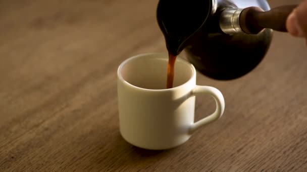 木製のテーブルの上にカップにトルココーヒーを入れてください 朝のコーヒールーチン 熱い蒸し黒コーヒー — ストック動画