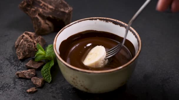 自宅でチョコレートフォンデュ 溶かしたダークチョコレートにバナナのスライスをダイピング — ストック動画