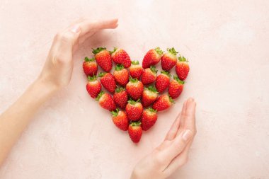 Hands holding heart of strawberries