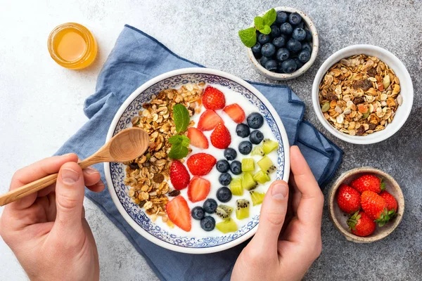 Person eating yogurt with granola and fruits — 스톡 사진