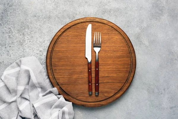 Round wooden cutting board and cutlery, food background — Stok fotoğraf