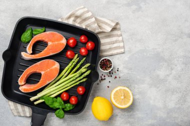 Uncooked salmon steaks and vegetables on metal grill pan