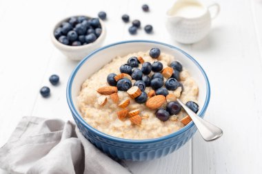 Healthy breakfast oatmeal porridge in bowl with blueberries and almonds clipart